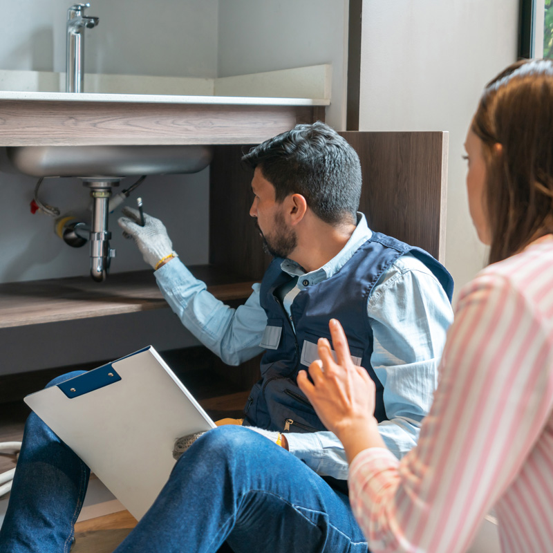 plumbing looking at pipes with homeowner