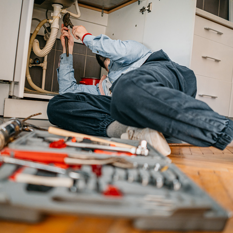 plumbing working under a sink